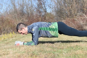 Coach Chris performing a plank outside.