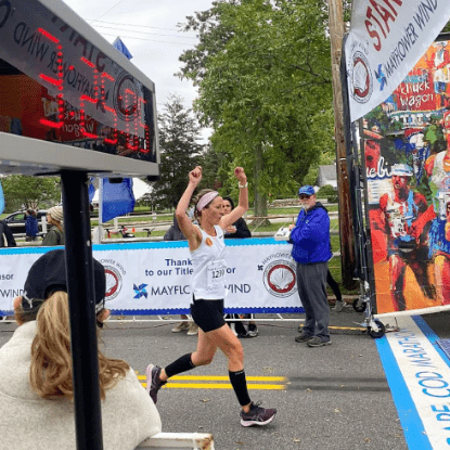 Woman finishing marathon with arms raised.