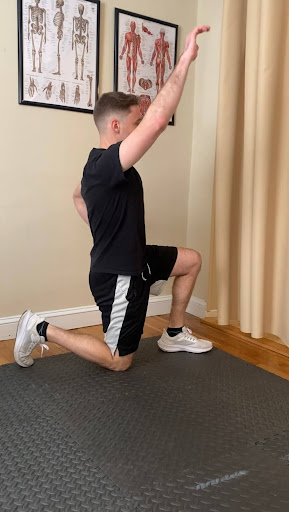 Alex Burke, PT demonstrating how to perform a kneeling hip flexor stretch.