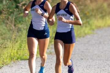 high school girls compete in a cross country running event.